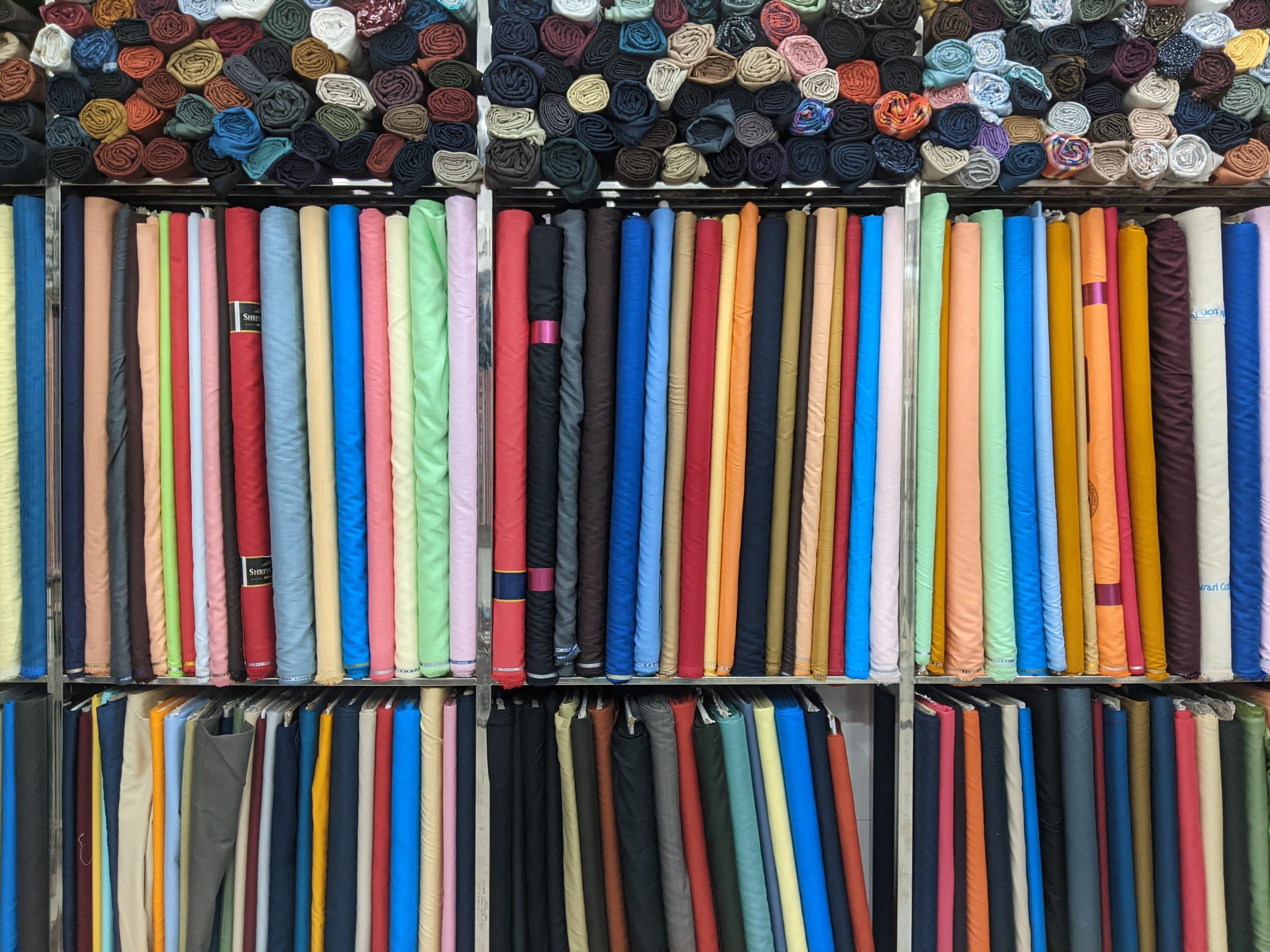 Rouleaux de tissus variés arrangés sur rayonnages